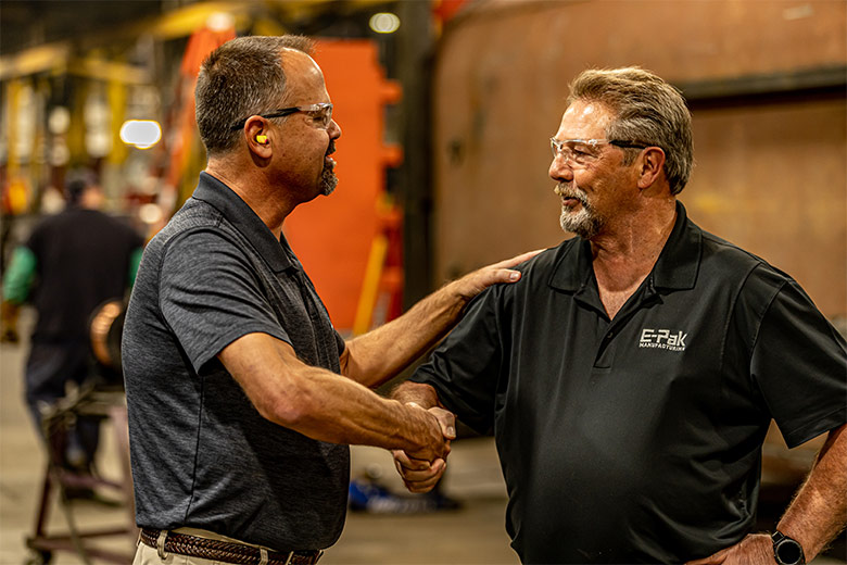 Two men in safety glasses shaking hands